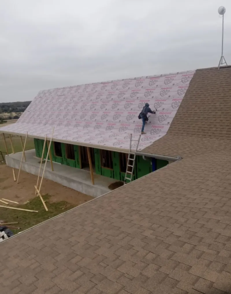 Worker preparing underlayment for a metal roof installation in Owosso